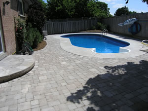 After: swimming pool with surrounding interlocking stone deck with steps and plantings