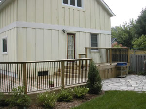 After: second story board & batten addition with deck, stone patio, fencing, and plantings